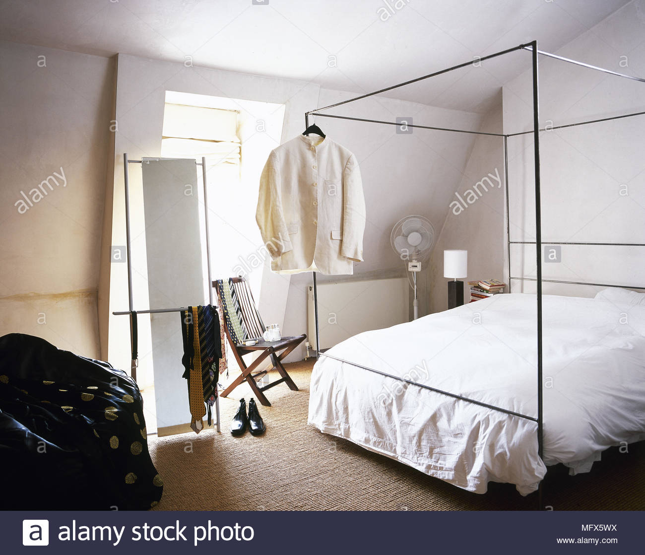 modernes schlafzimmer mit teppichboden dachschrage sonnigen fenster und herrenbekleidung hangen von einem metall himmelbett mfx5wx